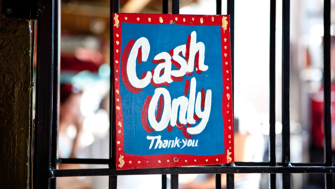 鉄柵に取り付けられた手描きの看板。「Cash Only Thank you」と書かれている