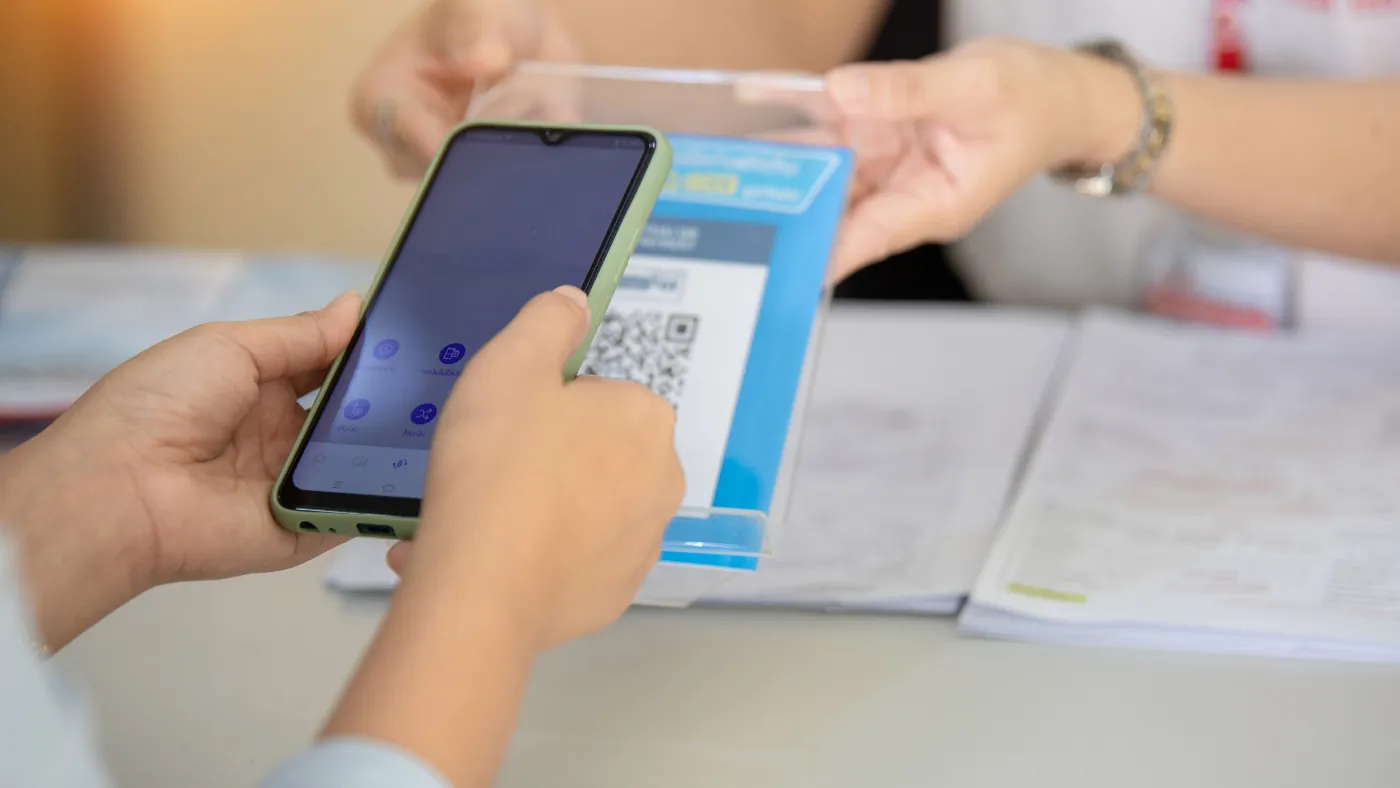 レジ横に置かれたQRコードを、客がスマートフォンで読み取ろうとしている