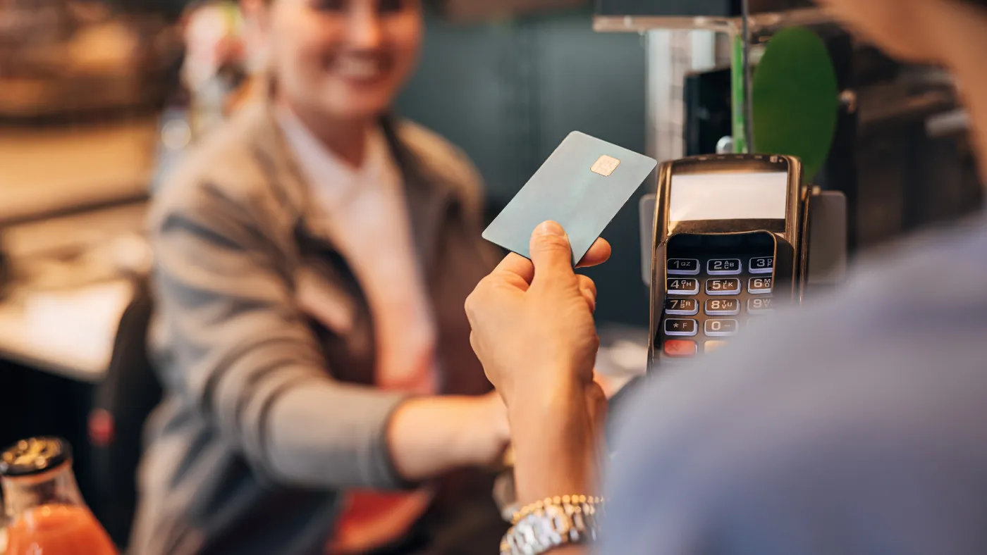 お客様が差し出したカードを、店員が持った決済端末で読み取ろうとしている