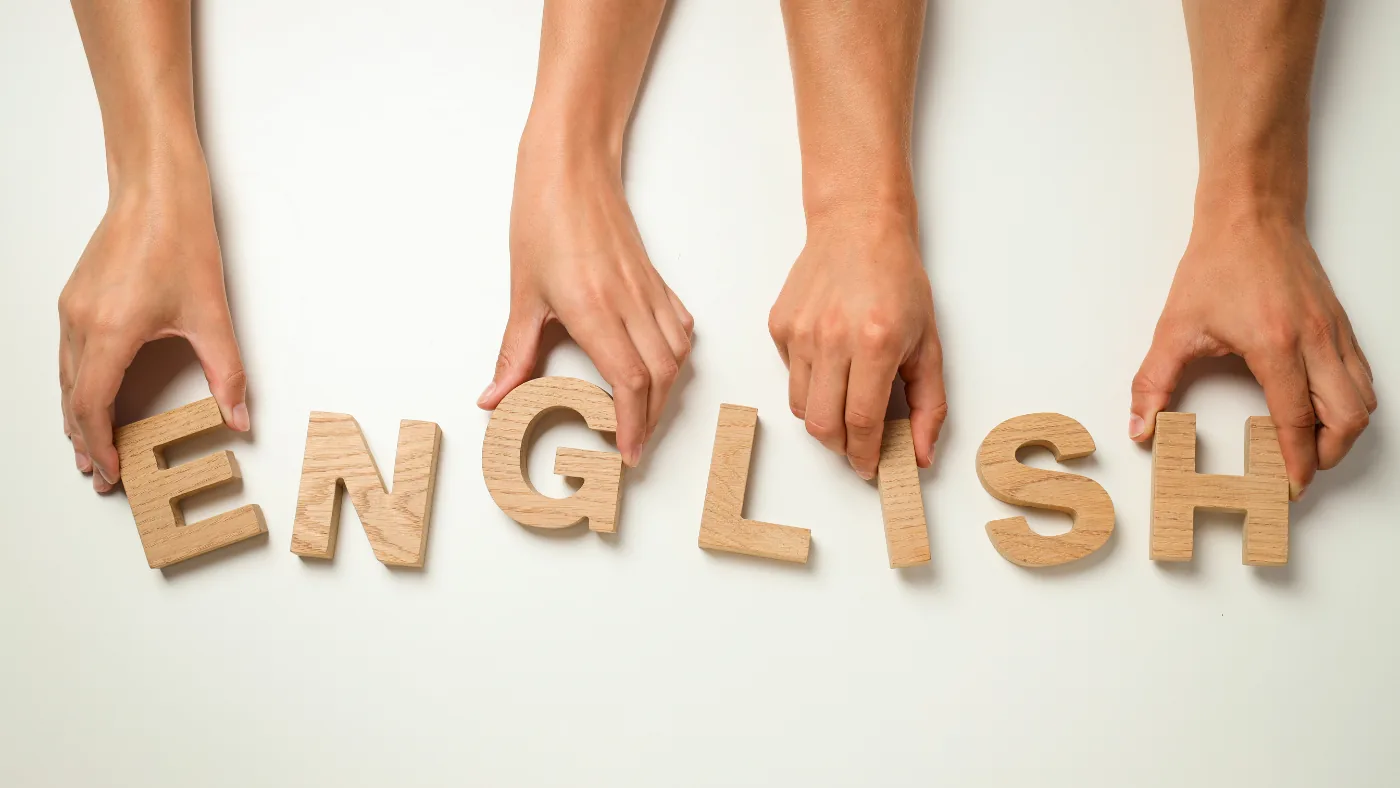 木製のアルファベットを両手で並べて「ENGLISH」と組んでいるところ