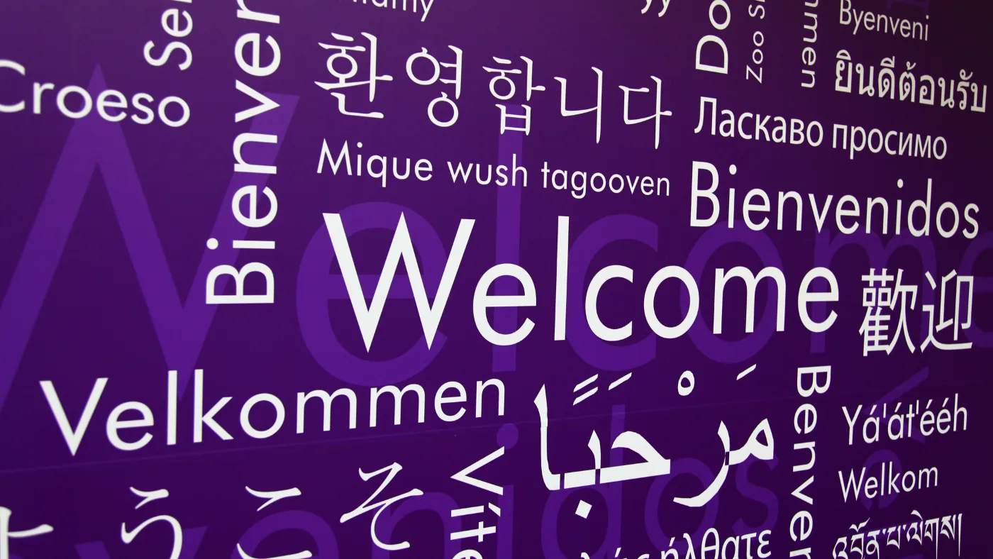 紫の壁一面に、世界各国の言語で「ようこそ」の言葉が並んでいる。中央に大きく Welcome の文字