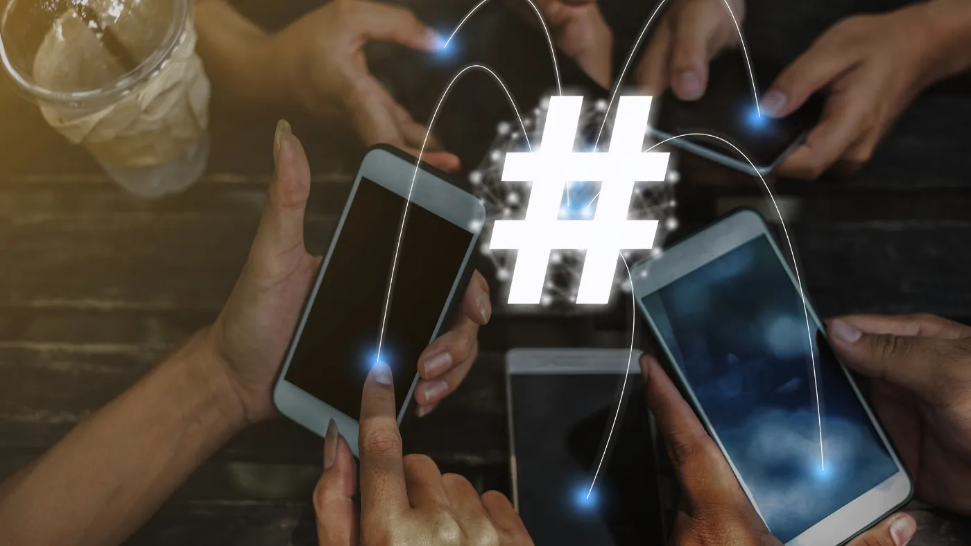 テーブルの上で何人かがスマートフォンを持ち、画面から伸びた光の線が中央の白い「#」の印につながっている