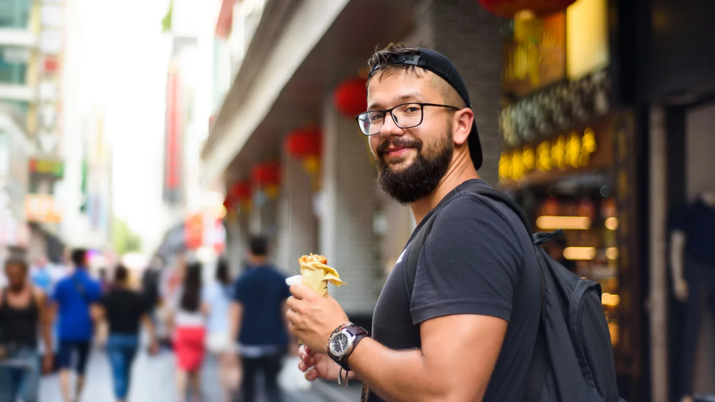 商店街を歩きながら食べ歩きをする外国人旅行者