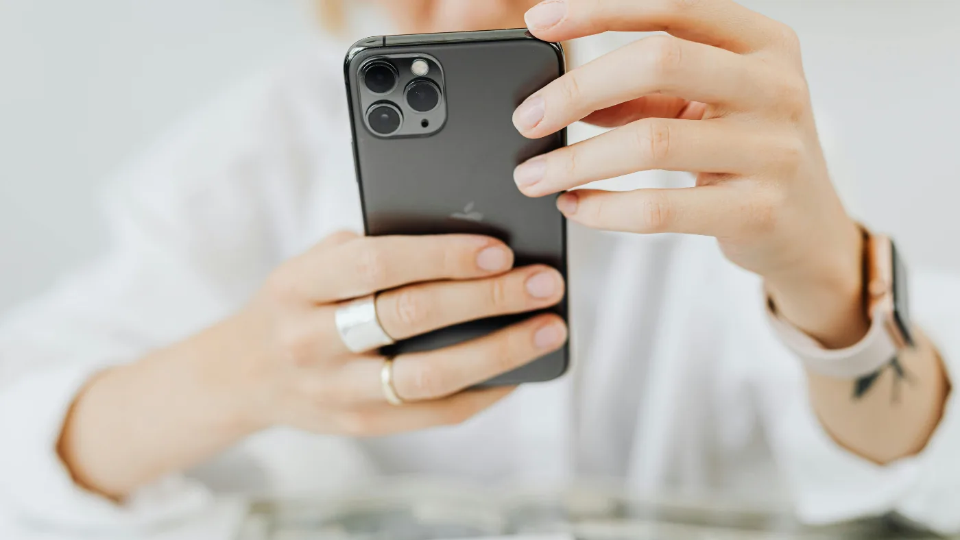 スマートフォンを両手で構えて何かを写そうとしている手元