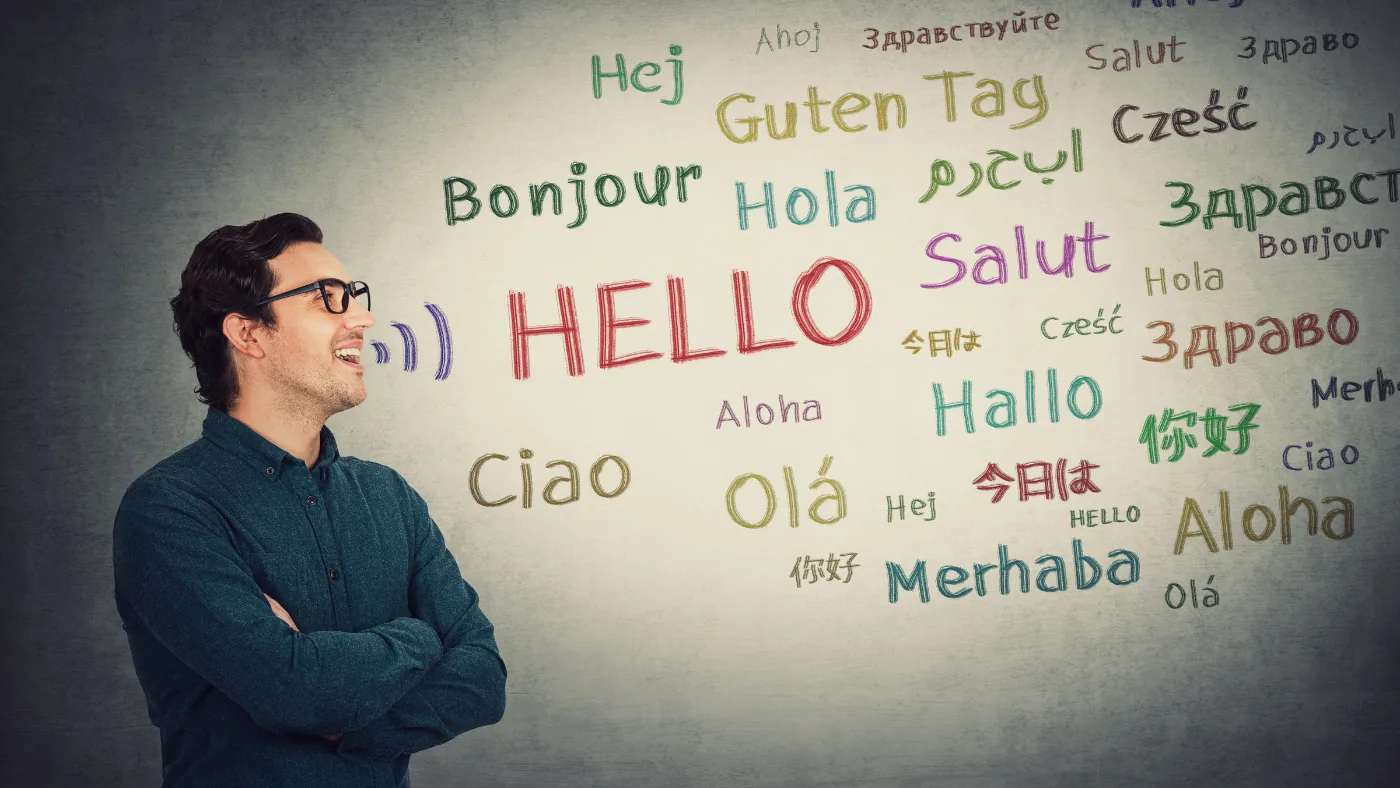 壁に書かれたいろいろな言語の「こんにちは」を見上げている人